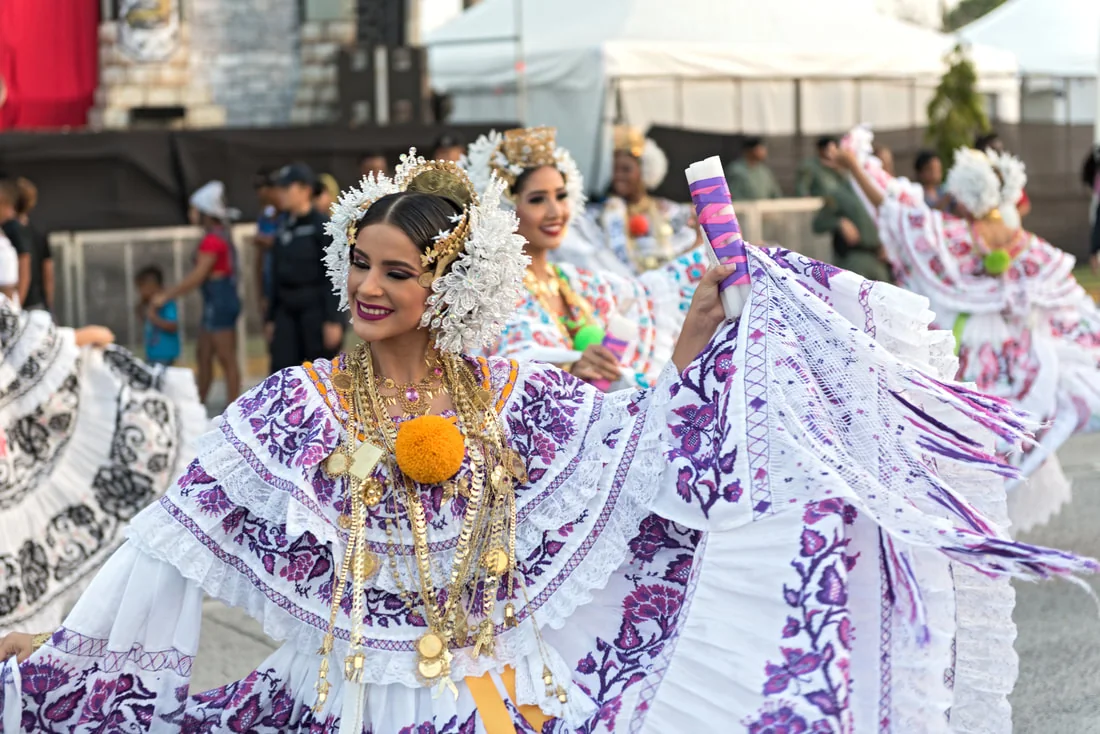 Bailarina con pollera blanca y morada, tembleques y joyas de oro, durante un desfile