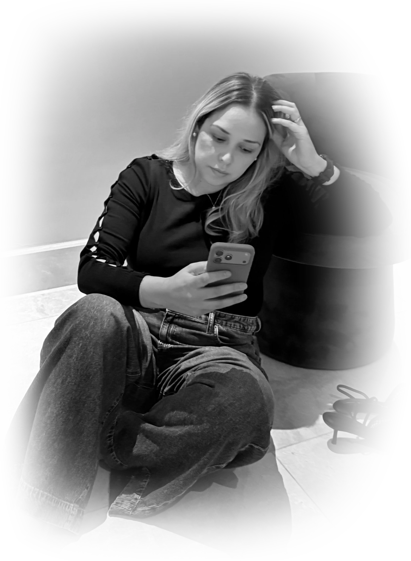Laura sentada en el suelo con el móvil, junto a un sillón y sus zapatos